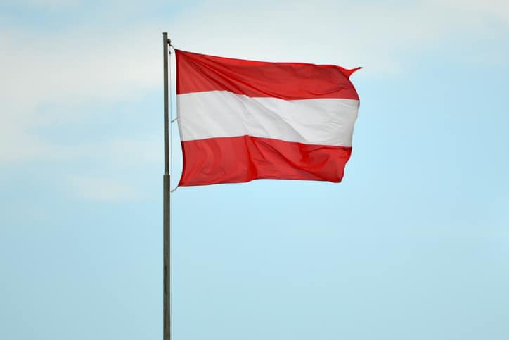 Horizontal view of the flag of Austria against cloudless sky.